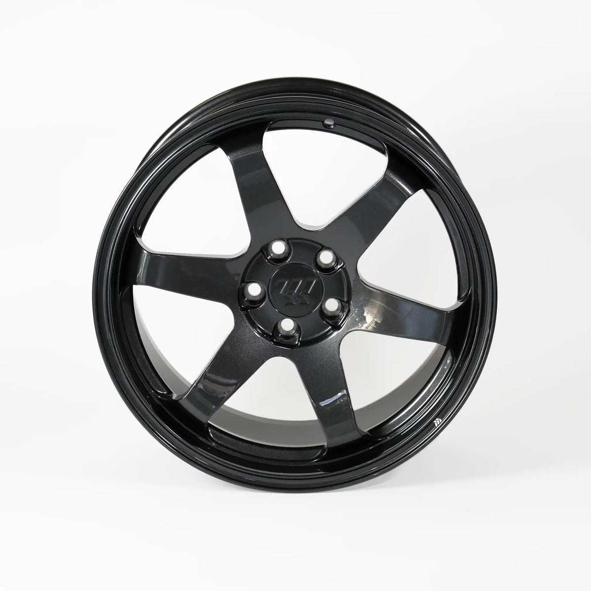 A glossy black multi-spoke alloy wheel rim with a five-bolt center hub, photographed against a seamless light gray studio background.