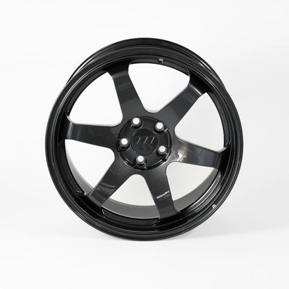 A glossy black multi-spoke alloy wheel rim with a five-bolt center hub, photographed against a seamless light gray studio background.