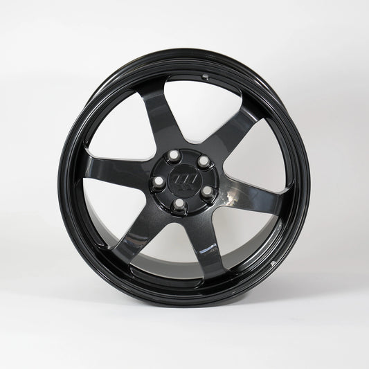 A glossy black multi-spoke alloy wheel rim with a five-bolt center hub, photographed against a seamless light gray studio background.
