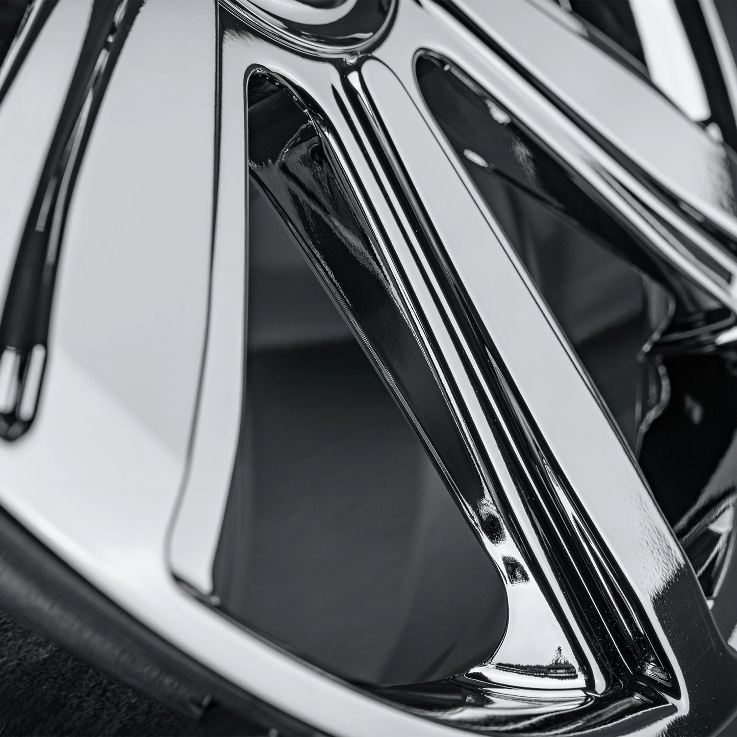 Close-up of a polished chrome multi-spoke car wheel rim showing reflective metallic surfaces and dark recessed areas.