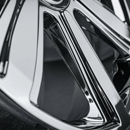Close-up of a polished chrome multi-spoke car wheel rim showing reflective metallic surfaces and dark recessed areas.
