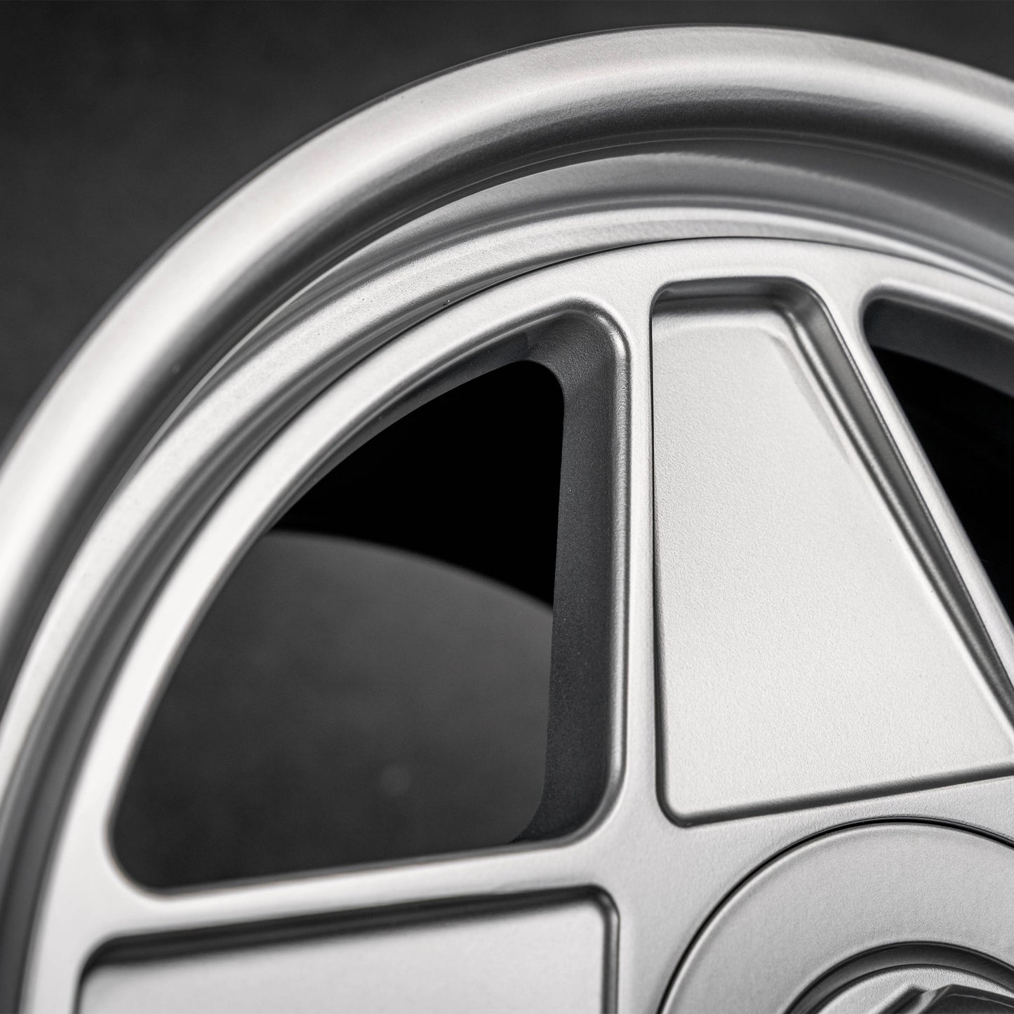 Close-up of a silver multi-spoke alloy car wheel rim with a dark background.