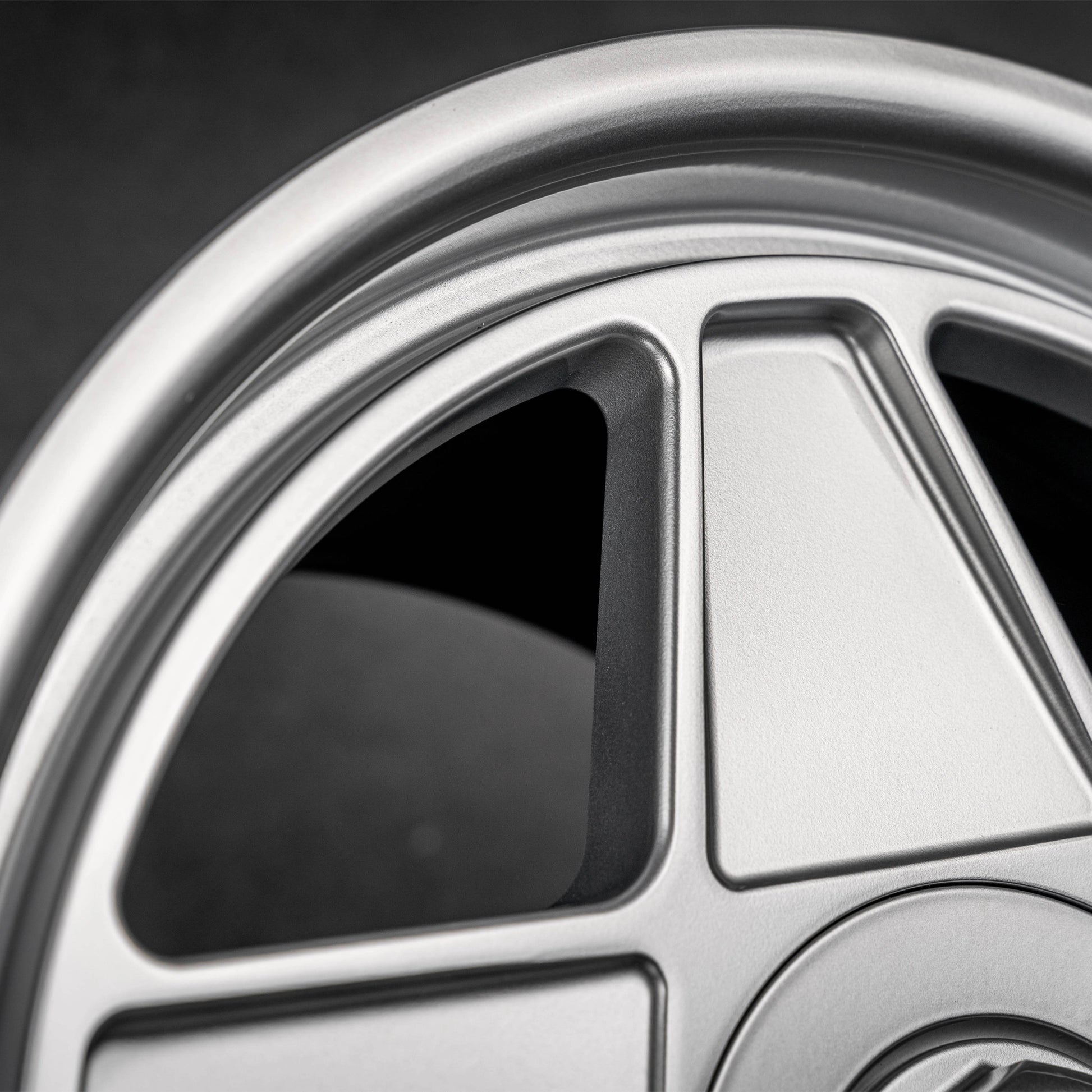 Close-up of a silver multi-spoke alloy car wheel rim with a dark background.
