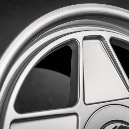 Close-up of a silver multi-spoke alloy car wheel rim with a dark background.