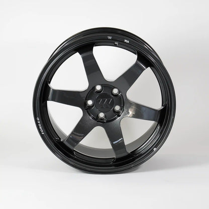A glossy black multi-spoke alloy wheel rim with a five-lug center cap, photographed against a seamless light gray studio background.