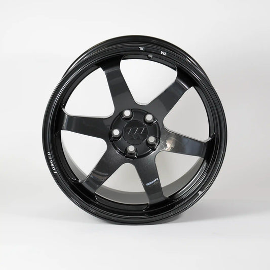 A glossy black multi-spoke alloy wheel rim with a five-lug center cap, photographed against a seamless light gray studio background.